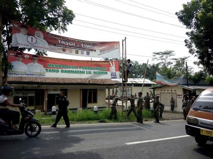 Petugas gabungan dari KPU, Satpol PP, PPK dan PPS memberbaiki APK yang rusak di tepi ruas jalan raya Mrebet